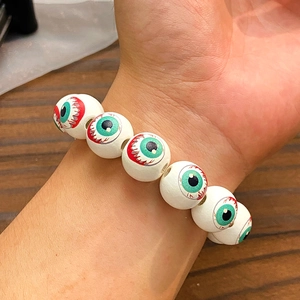 Détail d'un bracelet d'Halloween perlé blanc avec motifs d'yeux verts ensanglantés
