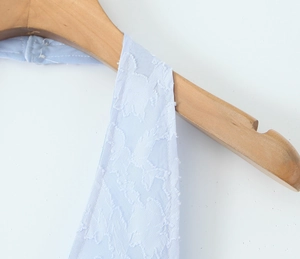 Detail of light blue floral jacquard fabric on a halter dress with textured pattern