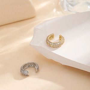 Detail showing gold and silver C-shaped ear bone clips with micro-set zircon crystals