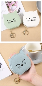Detailed close-up of mini cartoon cat coin purses with embroidery and metal keychains