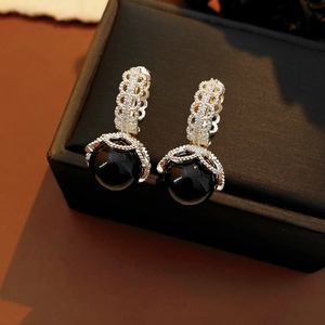 Detail of vintage earring with filigree lace metalwork and glossy black bead drop
