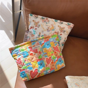 Close-up of quilted cotton pouches featuring bear and rainbow prints on a sofa