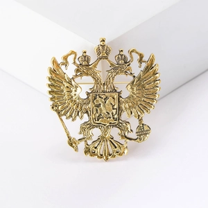 Vintage gold double-headed eagle brooch with crown and scepter on a white background