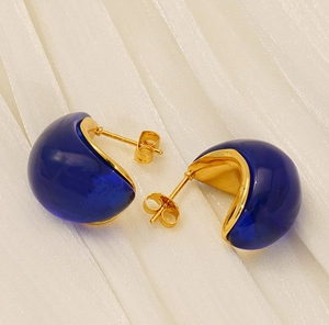 Detail of 18K gold-plated titanium earrings with deep blue resin inlay on white silk
