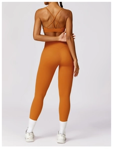 Rear view of ginger orange high-waisted yoga leggings and cross-back sports bra