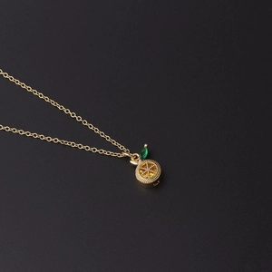 Detailed view of a gold chain necklace with a zircon-encrusted orange slice fruit pendant