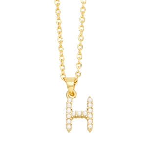 Macro detail of golden H-shaped pendant necklace featuring inlaid small white pearls