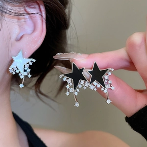 Close-up of star-shaped pendant earrings in black and white with sparkling zircon details