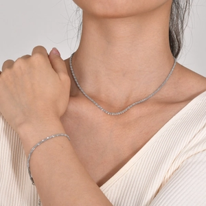 Sparkling tennis necklace and bracelet set in silver finish worn by a female model