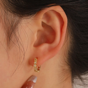 Minimalist gold heart hoop earrings with micro-set zircons on woman's earlobe