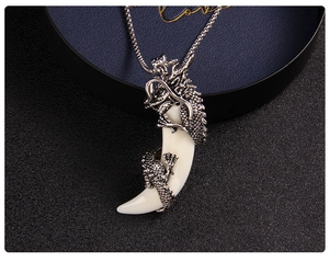 Macro detail of faux wolf tooth pendant with dragon metal wrap and vintage steel chain