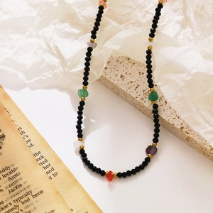 Detail of colorful seed bead necklace with natural stone accents on a white textured rock