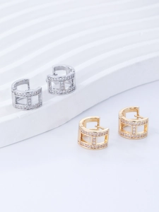 Close-up of gold and silver pavé hoop earrings featuring a cutout letter H design