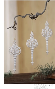 Close-up of three white and gold vintage Christmas ornaments hanging on branches