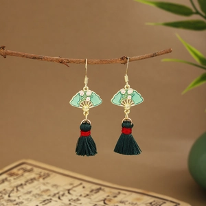 Detailed macro view of green fan-shaped tassel earrings hanging on a dry branch