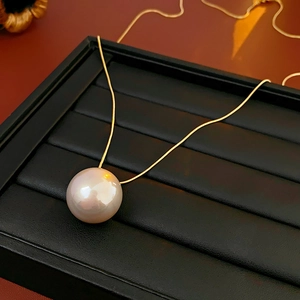Close-up of a high-luster pink-white pearl necklace on a refined golden snake chain