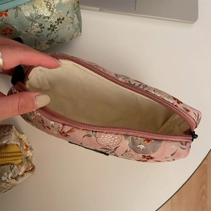 Detail of floral embroidery and spacious interior of the pink canvas cosmetic bag