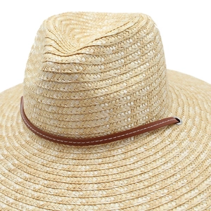 Detailed macro of woven straw texture and brown leather strap with silver buckle on sun hat