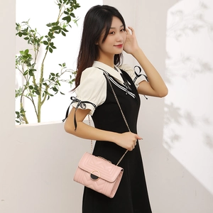 Pink quilted crossbody bag with V-shaped texture and gold chain strap shown on model
