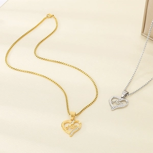 Detail of gold and silver heart Mom pendants with cubic zirconia on a warm beige backdrop
