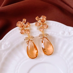 Détail de boucles d'oreilles vintage avec gouttes ambre et fleurs en zircons brillants