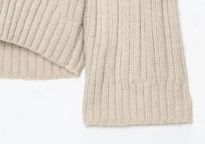 Macro detail of beige ribbed knit sweater showing soft fabric texture and vertical weave