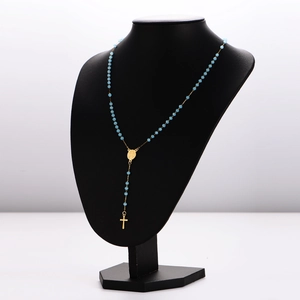 Long blue beaded rosary necklace with gold crucifix and medallion on black mannequin