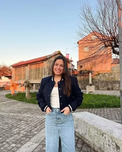 Close-up of navy blue baseball collar jacket paired with a denim skirt in outdoor setting