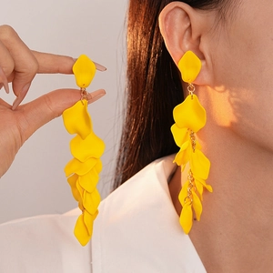 Macro detail of yellow petal tassel earrings with gold chains on model ear
