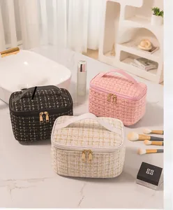 Three elegant tweed makeup bags with dual zippers and handles on a bathroom counter