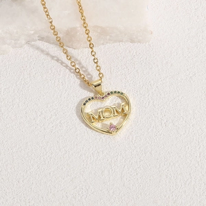 Golden heart MOM necklace pendant with colorful gemstones on a white stone background