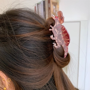 Detail of pink marble acetate dinosaur hair claw clip styled on long brown hair