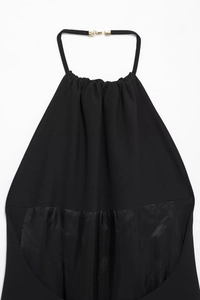 Detail des eleganten schwarzen Neckholder-Kleids mit Satin-Saum und glattem Stoff