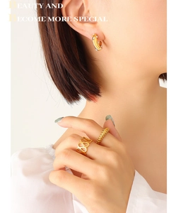 Close-up of gold titanium C-shaped earrings with pearls and geometric zircon rings