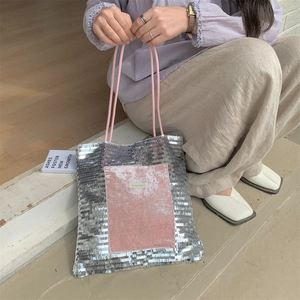 Close-up of silver sequin tote bag with pink velvet patch and woven shoulder straps