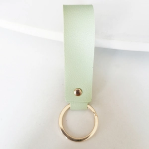 Detail view of light green leather keychain strap with premium gold metal ring