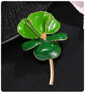 Macro shot of green enamel iris flower brooch with gold plated edges on a textured tray