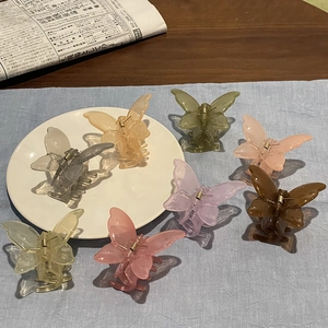 Selection of translucent butterfly hair claws in multiple soft colors on a porcelain tray