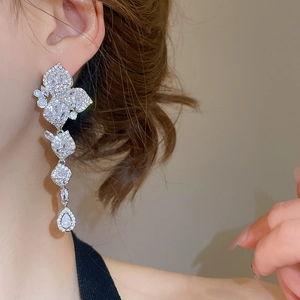 Macro detail of silver tassel earrings with sparkling leaf zircon and teardrop pendants