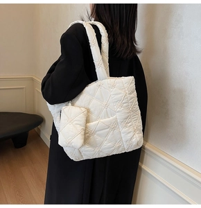Detail of white quilted tote bag featuring floral embroidery and matching small pouch