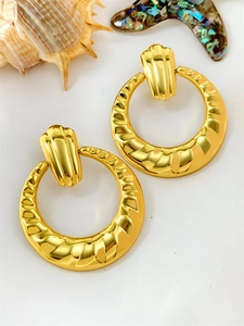 Detailed macro shot of vintage gold geometric earrings with textured shell ear studs