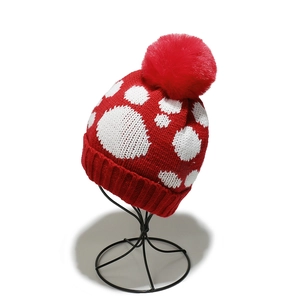 Nahaufnahme der roten Strickmütze mit weißen Punkten und großem Kunstfell-Bommel