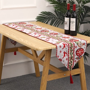 Detailed view of knitted Christmas table runner with festive reindeer patterns and tassels