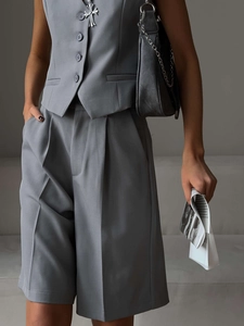 Detailed macro view showing the textured grey fabric and button of the fitted vest suit
