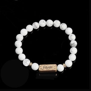 Macro detail of natural howlite beaded bracelet with vintage gold Faith engraved charm