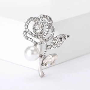 Elegant silver rose brooch with sparkling rhinestones and white pearl on white pedestal
