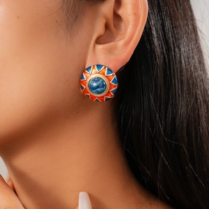 Close-up of geometric floral resin earring with blue gemstone and colorful enamel details