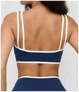 Detail of the navy yoga bra showing the dual shoulder straps and white contrast piping