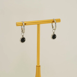 Close-up of silver earrings with round black stones and delicate metallic textures
