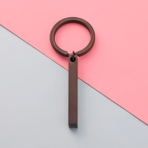 Detailed close-up of matte bronze rectangular bar keychain on a dual-tone background